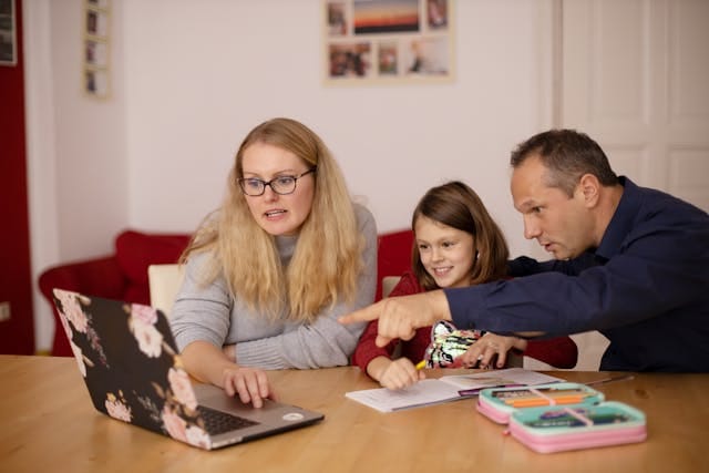 A homeschool family learning together at a laptop in a warm living room